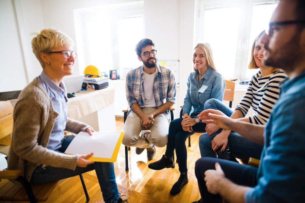 People sitting in group therapy smiling. 