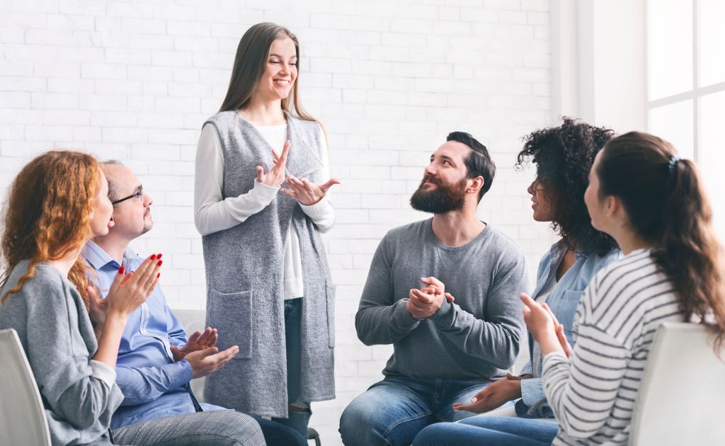 A happy woman sharing her recovery story in group therapy