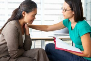A compassionate therapist offers a supportive hand to a female client during a one-on-one therapy session.