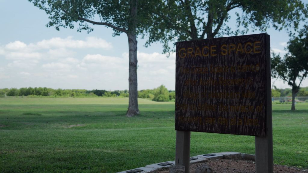 Wooden sign reading “Grace Space” in green park