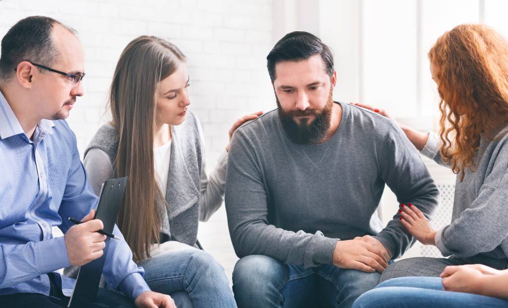 People in group therapy supporting a group member