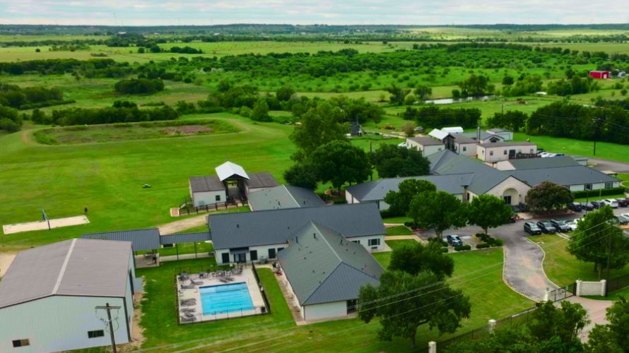 Aerial view of the Infinite Recovery campus surrounded by green fields in Texas.
